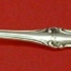 Puede incluir: Una cucharita de plata con un mango curvo adornado.