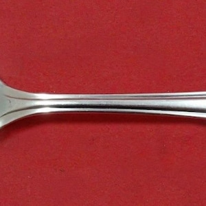 May include: A silver serving spoon with an ornate handle and a decorative cut-out design in the bowl.