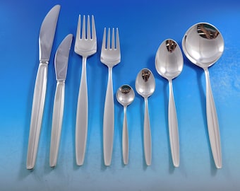 May include: A set of eight silver-plated flatware pieces, including a knife, fork, teaspoon, and tablespoon. The flatware has a modern, minimalist design with smooth, rounded edges.