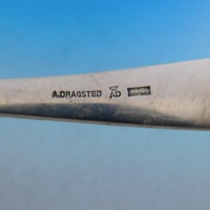 Puede incluir: Primer plano de la parte inferior de una pieza de cubiertos de plata con la inscripci&oacute;n "A. Dragasted AD Denmark".