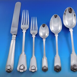 May include: A set of six silver-plated flatware pieces, including a knife, two forks, and three spoons. The handles are decorated with a shell design.