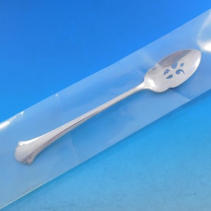 May include: A silver serving spoon with a decorative cut-out design. The spoon is in a clear plastic bag.