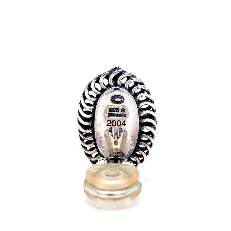 Puede incluir: Encanto de plata con un dise&ntilde;o ovalado detallado, que presenta una inscripci&oacute;n circular con el texto "925 S DENMARK 2004".