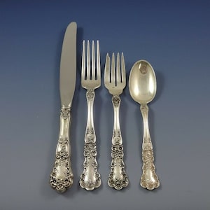May include: A set of four silver-plated flatware pieces, including a knife, two forks, and a spoon. The pieces have an ornate, floral design.