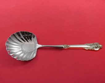 May include: A silver serving spoon with a scalloped bowl and an ornate handle.
