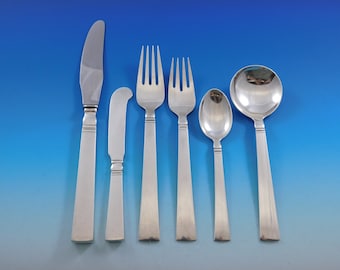 May include: A set of six silver-plated flatware pieces, including a knife, butter knife, two forks, a teaspoon, and a soup spoon. The flatware has a simple, modern design with squared handles.