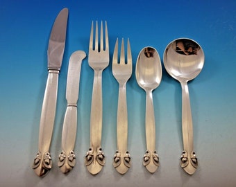May include: A set of six silver-plated flatware pieces with acorn-shaped handles. The set includes a knife, a butter knife, a dinner fork, a salad fork, a soup spoon, and a teaspoon.