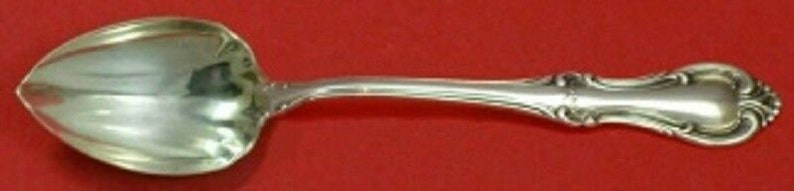 Puede incluir: Una cuchara de az&uacute;car de plata con un mango decorativo y un cuenco redondeado.