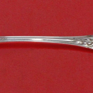 May include: A silver serving spoon with an ornate handle and a pierced bowl. The bowl has a decorative design of a stylized flower.