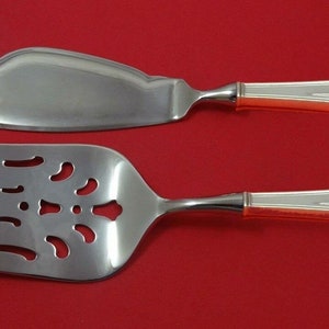 May include: A silver cake server and fork set with ornate handles. The handles have a geometric design and are made of silver.