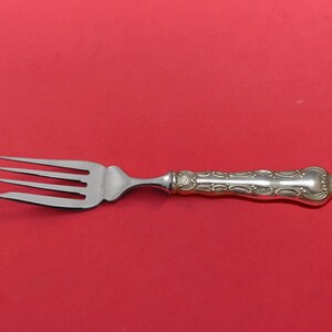 May include: A silver fork with an ornate handle. The fork has four tines and a polished finish.