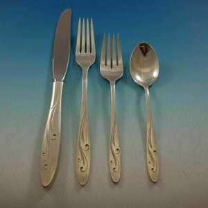 May include: A set of four silver-plated flatware pieces, including a knife, fork, and two spoons. The handles are decorated with a swirling leaf design.