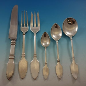 May include: A set of six silver-plated flatware pieces, including a knife, fork, and four spoons. The pieces have a simple, elegant design with a pointed tip and a decorative handle.