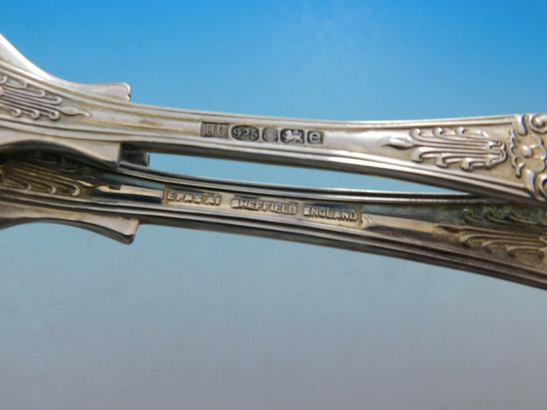 May include: Close-up of the underside of two silver spoons. The spoons are marked with "EPNS" and "Sheffield England". One spoon is also marked with "U 925 XE".