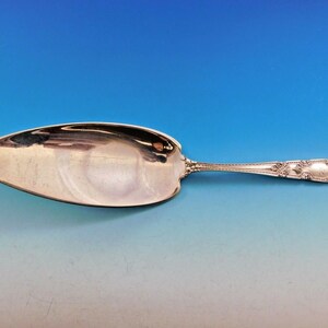 May include: A silver cake server with an ornate handle and a leaf-shaped blade.