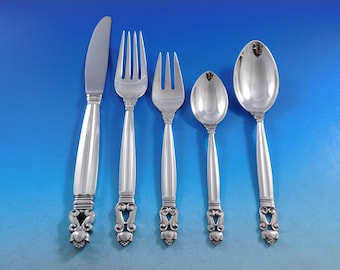 May include: A set of five silver-plated flatware pieces, including a knife, two forks, a teaspoon, and a tablespoon. The handles are ornate and feature a stylized design.
