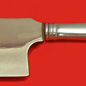 May include: A stainless steel cleaver with a polished finish. The blade has a rectangular shape with a hole near the top. The handle is curved and features a decorative design at the end. The text "STAINLESS STEEL" is visible on the blade.