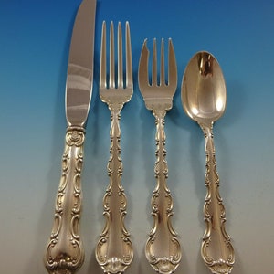 May include: A set of four silver-plated flatware pieces, including a knife, fork, teaspoon, and a larger fork. The pieces have an ornate, decorative design with a floral pattern.