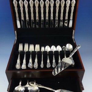 May include: A wooden box with a black velvet interior containing a set of silver flatware. The box has a drawer that holds additional pieces of silverware.