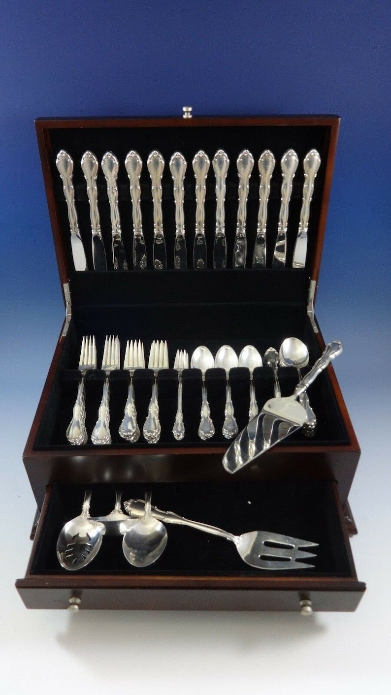May include: A wooden box with a black velvet interior containing a set of silver flatware. The box has a drawer that holds additional pieces of silverware.