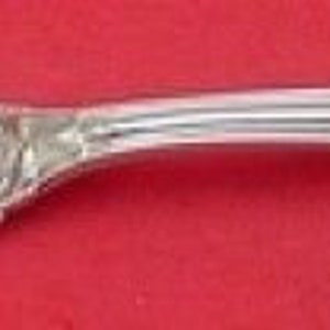 May include: A silver two-pronged fork with an ornate handle. The fork is designed for serving food.