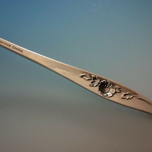 May include: Close-up of a silver fork with a floral design and the inscription "Heirloom Sterling" on the handle.