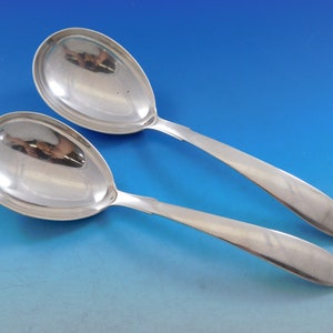 Puede incluir: Dos cucharas de servir de plata con acabado pulido. Las cucharas tienen un cuenco redondeado y un mango largo y delgado.