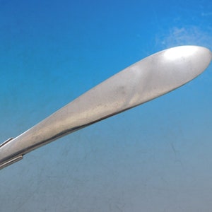 Puede incluir: Primer plano de la parte posterior de una cuchara de plata con un mango liso y redondeado.