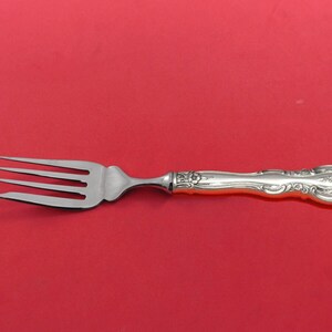 May include: A silver fork with an ornate handle. The fork has four tines and a polished finish.