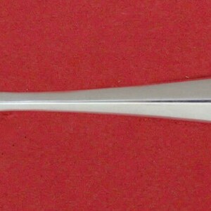 May include: A silver serving spoon with a unique design. The spoon has a rounded bowl with a hole in the center and a long, slender handle.