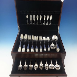 May include: A wooden box with a black velvet interior containing a set of silver flatware. The box has a drawer that holds additional pieces of silverware.