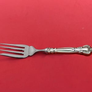 May include: A silver fork with a decorative handle. The fork has four tines and a smooth, polished finish.