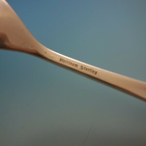 May include: Close-up of the back of a silver spoon with the inscription "Heirloom Sterling" on the handle.
