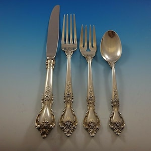 May include: A set of four silver-plated flatware pieces, including a knife, fork, and two spoons. The handles are ornate and feature a floral design.