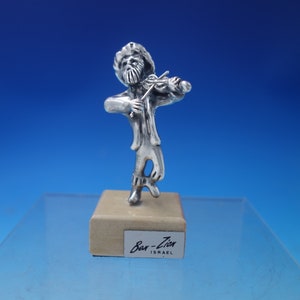May include: Silver figurine of a man playing a violin, standing on a small wooden base with the text "Bar-Zion ISRAEL" on it.