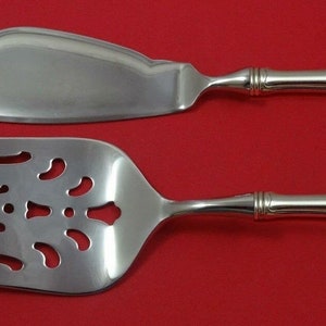 May include: A silver cake server and fork set with ornate handles. The server has a smooth, rounded blade and the fork has an openwork design.