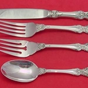 May include: A set of four silver-plated flatware pieces, including a knife, fork, and two spoons. The pieces have ornate handles with a floral design.