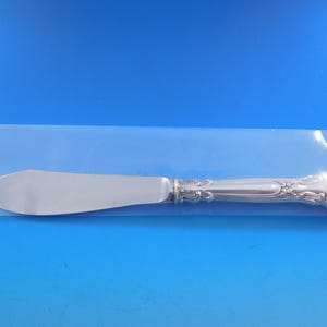 May include: A silver butter knife with an ornate handle. The knife is in a clear plastic bag.