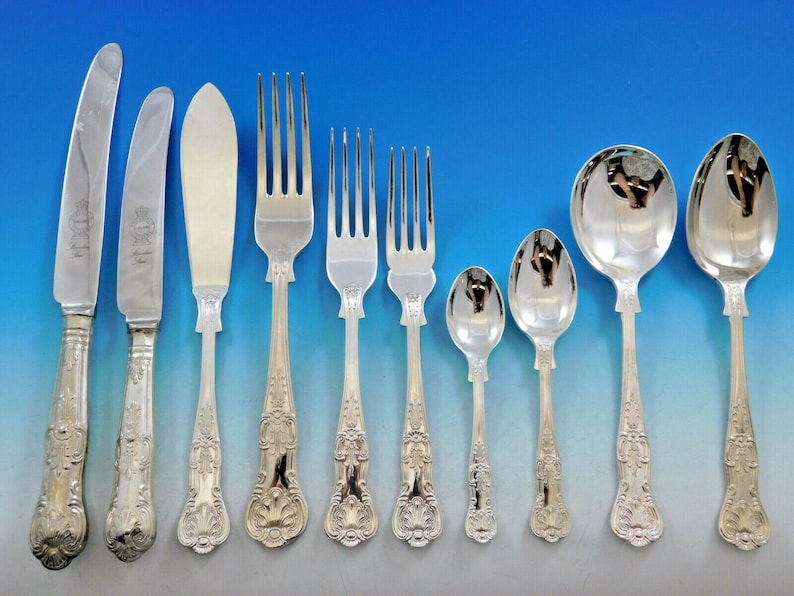 May include: A set of silver flatware with ornate handles. The set includes a dinner knife, a butter knife, a dinner fork, a salad fork, a teaspoon, a soup spoon, and a dessert spoon.