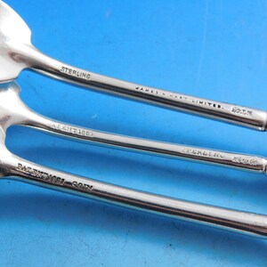 May include: Close-up of the back of three silver spoons with the inscription "STERLING" and "JAMES M. HART LIMITED." The spoons also have the inscription "PATENT 1867" and "PATENT 1862".