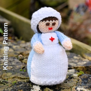 May include: A knitted nurse doll with a white cap, blue sleeves, and a white apron featuring a red cross. The doll has brown hair, a tan face, and red lips. The text "Knitting Pattern" is visible on the left. The doll is made of yarn.