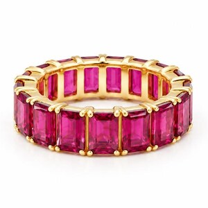 Peut inclure: Une bague éternité en or composée d'une rangée continue de pierres précieuses roses rectangulaires taille émeraude, serties dans une monture en or jaune poli. La bague présente un design uniforme avec chaque pierre fixée par des griffes.