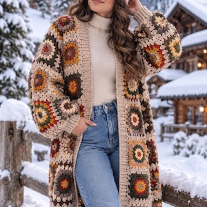 Puede incluir: Un cárdigan de ganchillo de manga larga con un patrón de cuadrados de la abuela multicolor en tonos beige, marrón, amarillo y rojo oscuro, combinado con un suéter de cuello alto de canalé beige, vaqueros azules y un gorro de punto beige a juego.