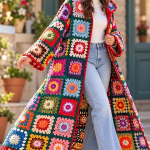 Puede incluir: Un abrigo largo con capucha confeccionado con parches de ganchillo tipo granny square en tonos rojo, verde, azul, amarillo y rosa, con una base verde oscuro, mangas largas y un borde de ganchillo rojo a lo largo del frente y el dobladillo.