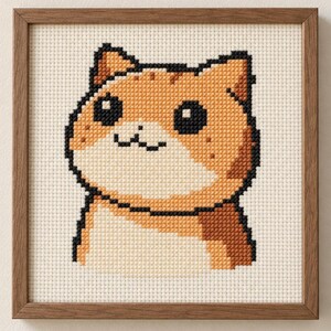 Könnte beinhalten: Ein quadratisches Kreuzstich-Stickbild mit einer verpixelten orange-weißen Katze mit großen schwarzen Augen und einem kleinen Mund auf cremefarbenem Stoff, eingefasst in einen schlichten, dünnen Holzrahmen in mittlerem Farbton.