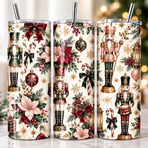 Op de afbeelding: Drie cilindrische bekers met zilveren rietjes voorzien van een kerstpatroon op een crèmekleurige achtergrond. Het ontwerp bevat notenkrakers, rode kerststerren, groene dennentakken, zuurstokken, gouden sterren en rode strikken.