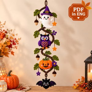 May include: A vertical crochet wall hanging featuring a brown vine with green leaves, a white ghost wearing a purple witch hat, a purple owl, an orange jack-o'-lantern, and a black bat. Small orange stars, purple flowers, and acorns hang from the vine.