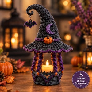 May include: A crocheted witch hat lantern in dark gray with a purple trim, featuring a small orange pumpkin, a purple crescent moon, and a dangling bat charm. The base is constructed with purple twisted pillars holding a white LED tea light candle.