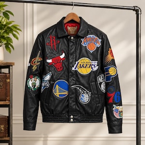 May include: A black leather varsity jacket featuring a spread collar, long sleeves, and a ribbed hem. The jacket is adorned with various colorful embroidered patches of professional basketball team logos and symbols across the front and sleeves.