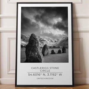 May include: A black and white framed wall art print featuring the Castlerigg Stone Circle in the United Kingdom. The text reads Castlerigg Stone Circle, 54.6016° N, 3.1192° W, and United Kingdom below the landscape photograph.